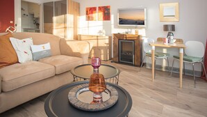 A modern living room with a sofa, coffee table, fireplace, and a dining area with chairs and a table. - Small Studio in Neuastenberg With Balcony (Winterberg)