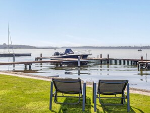 A marina with a dock, a small boat, and two chairs facing the water.