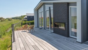 A modern house with a deck, large windows, and a brick exterior. - House in Zeeland With Terrace by the Dyke (Wemeldinge)