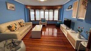 A living room with a sofa, a coffee table, a TV, and a window with curtains. - Bermeo Park - Centrica Casa Independiente (Bermeo)