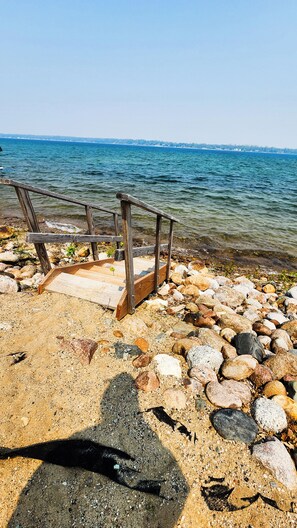 Un muelle de madera que se adentra en una masa de agua, rodeado de una costa rocosa.