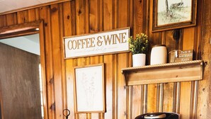 Una estación de café y vino de madera con una cafetera Keurig, una jarra de café blanca y un letrero que dice 'CAFÉ & VINO' Servido a diario.