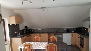 Une cuisine compacte avec un coin repas, comprenant une table avec des chaises, une machine à café et un lave-vaisselle.