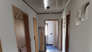 Un long couloir étroit, doté d’un sol carrelé et de portes en bois de chaque côté.