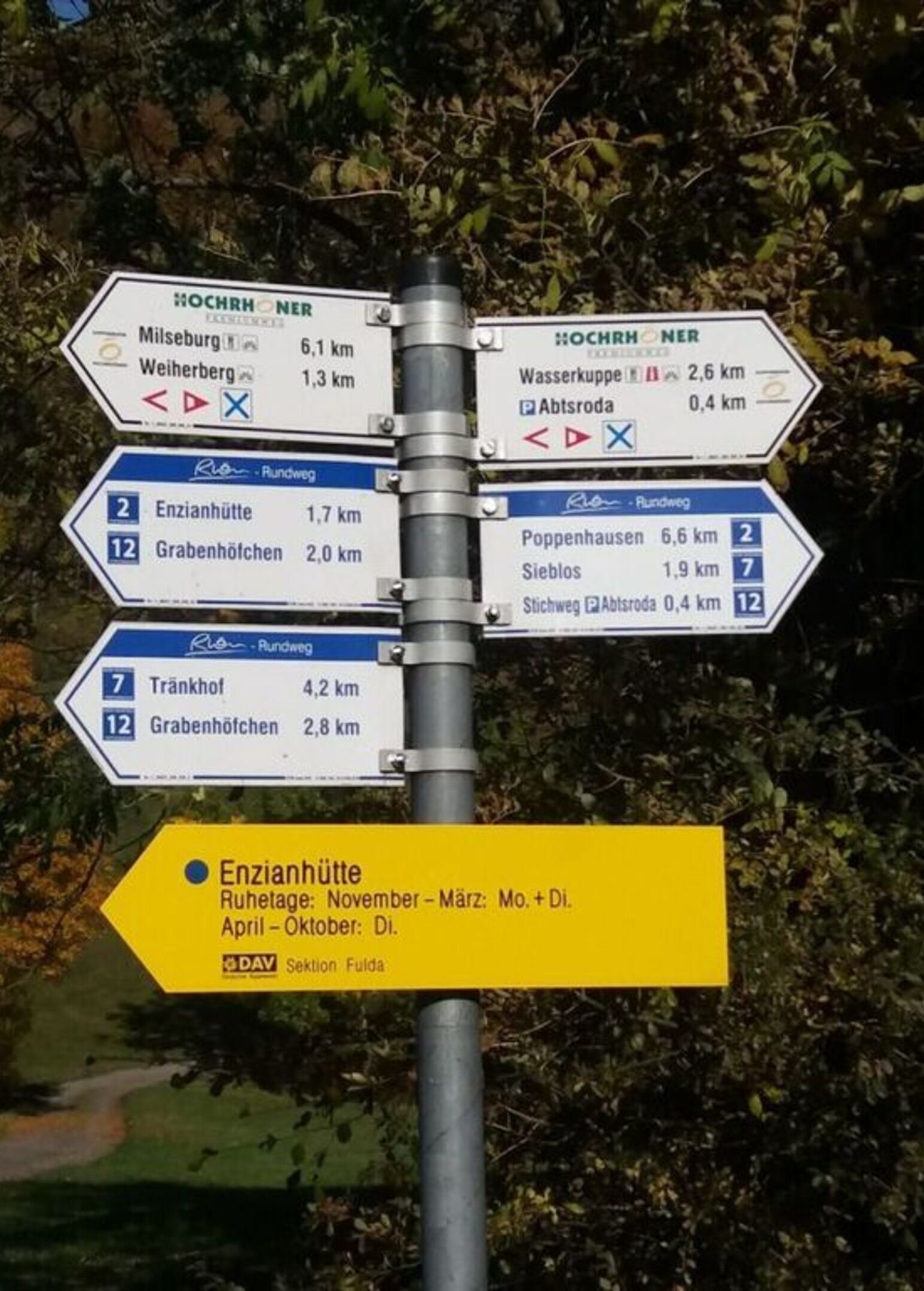 A directional signpost with multiple route options and distances to various destinations.