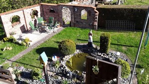 Une cour avec un bâtiment en briques, des sièges en plein air, un petit étang et une statue.