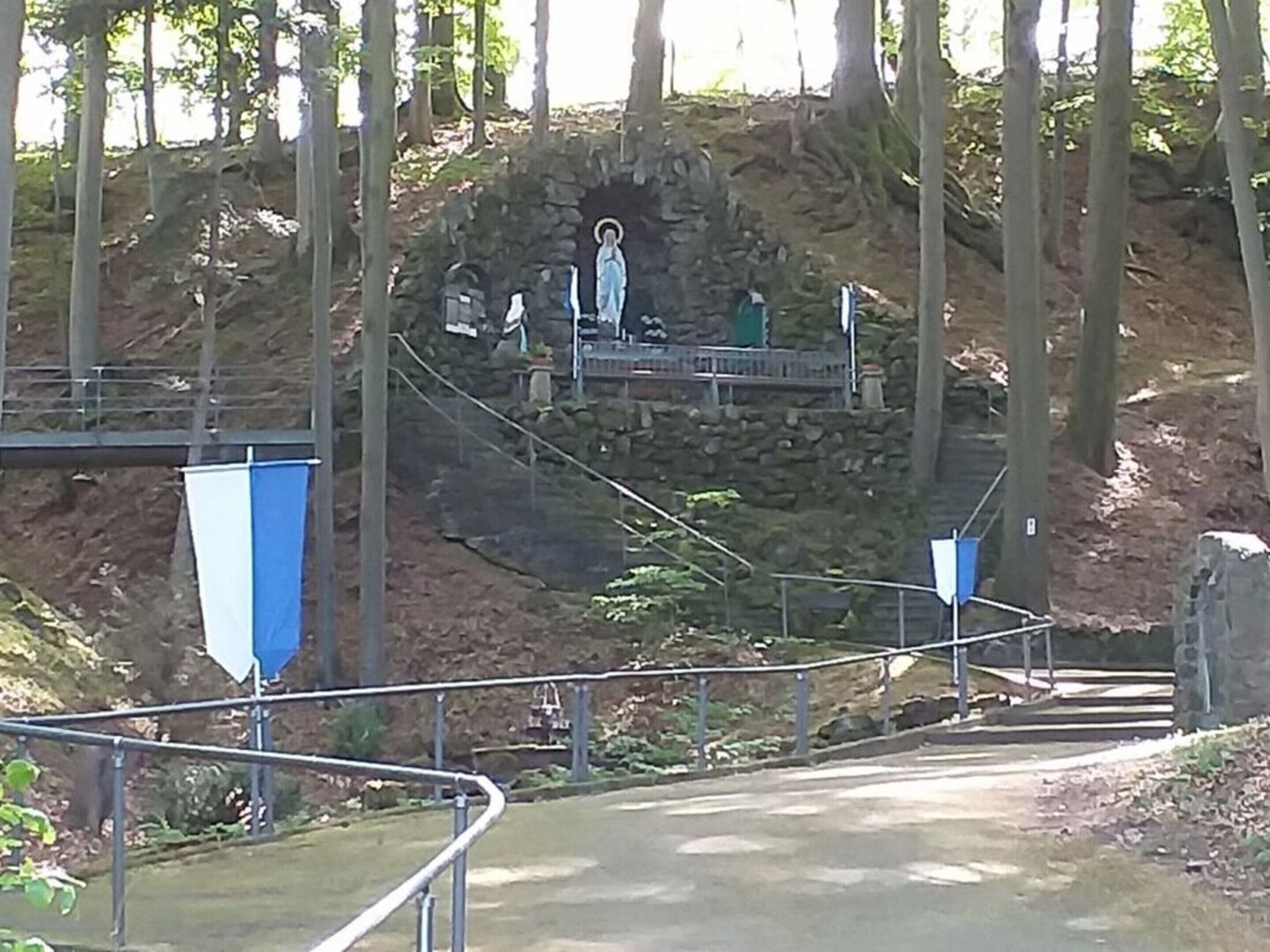 Un sendero de piedra que conduce a una estatua en un área boscosa.