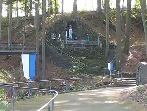 En stenlagd gång som leder till en staty i ett skogsområde.