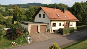 Une maison à deux étages avec un toit en pente, un garage et une allée pavée.