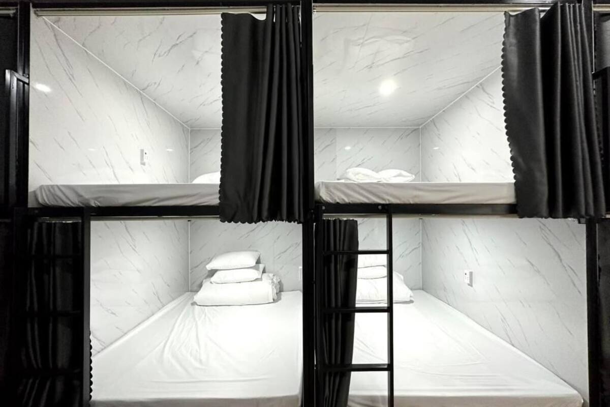 A bunk bed room with a marble-patterned ceiling and black curtains.