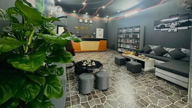 A modern reception area with a reception desk, seating area, and a large plant. - Long Huong Duy Hostel Ha Giang-BayLuxury (Ha Giang 2)