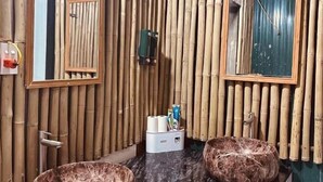 A bathroom with two round marble sinks, a bamboo wall, and a mirror. - Long Huong Duy Hostel Ha Giang-BayLuxury (Ha Giang 2)