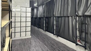 A hotel room with a dark wooden floor, a large window with black curtains, and a white tiled wall. - Long Huong Duy Hostel Ha Giang-BayLuxury (Ha Giang 2)