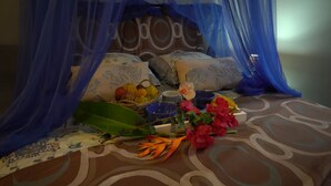 A bed with a canopy, pillows, a basket of fruits, a bowl, and a bouquet of flowers. - Saphir et sa Piscine à Débordement 3D Avec Bar à Punch Intégré (Saint-Joseph (Martinique))