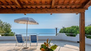 An outdoor patio with a view of the sea, two blue chairs, a white umbrella, and a potted plant. - Flat in Caprioli di Pisciotta With sea View (Pisciotta)
