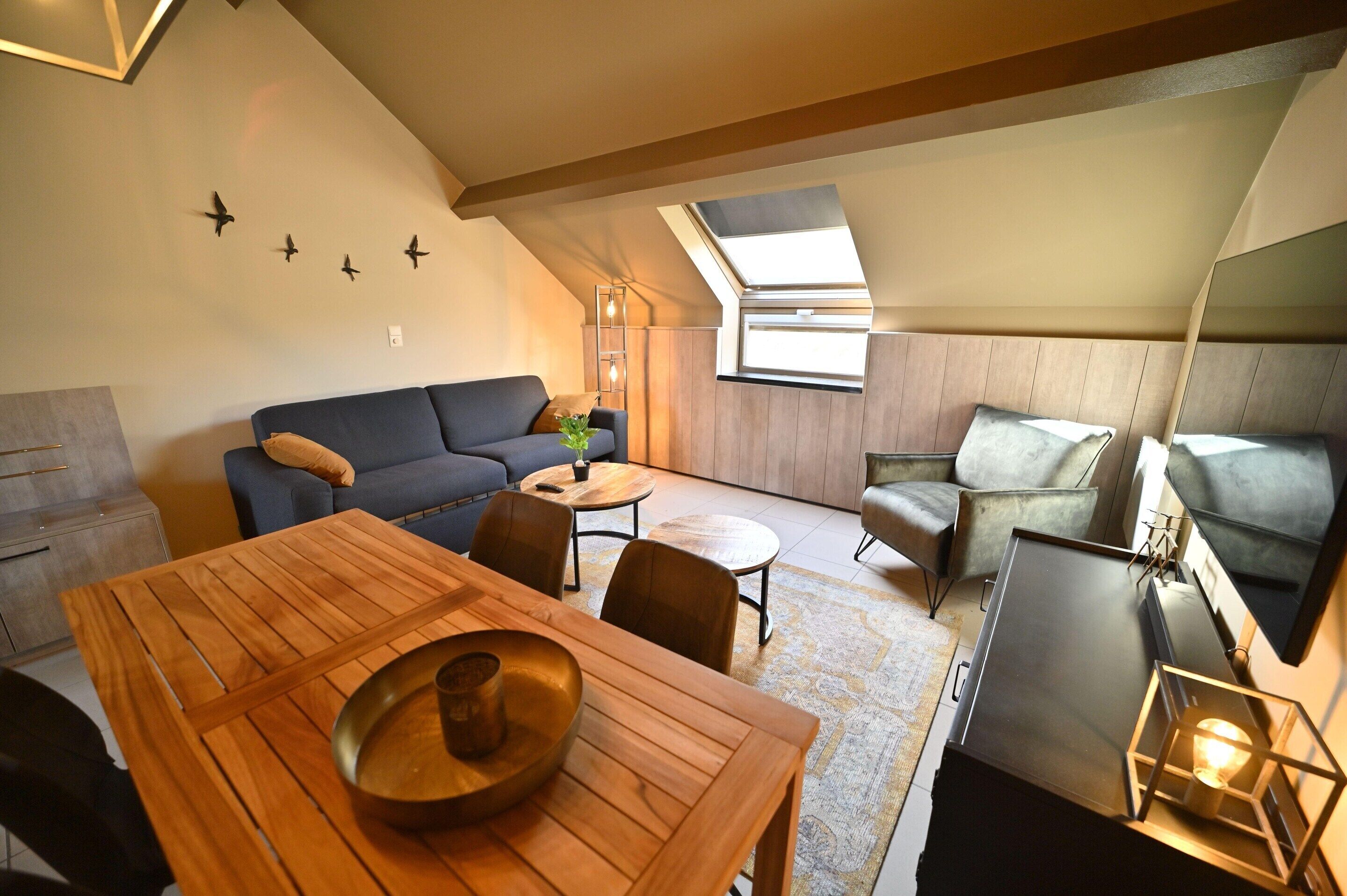 Um apartamento loft moderno com área de jantar, sofá e televisão.
