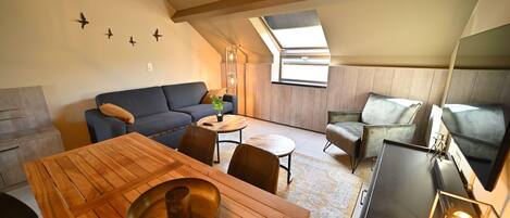 En moderne loftlejlighed med spiseplads, sofa og fjernsyn.