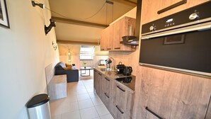 Eine moderne Küche mit Holzausstattung, einem eingebauten Ofen und einer Kaffeemaschine.