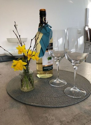 A bottle of wine, two wine glasses, and a vase with yellow flowers on a woven placemat. - Huus Schippe "stockholm" (Maasholm)