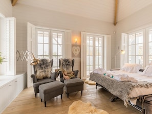 A cozy bedroom with a bed, two armchairs, a wooden floor, and large windows. - Holiday Home in Oostduinkerke (Koksijde)