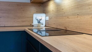 Et moderne køkken med træskabe, en indbygget komfur og en hvid bagplade med et hjortedesign.