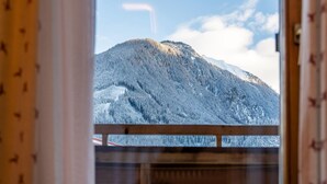 Vista de una montaña nevada a través de una ventana con marco de madera.