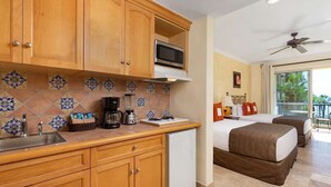 A hotel room with a kitchenette, a bed, a balcony with a view, and a ceiling fan. - Best Resort in Cabo, Right on Medano Beach, Wonderful Staff, Gourmet Dining, spa (Cabo San Lucas)