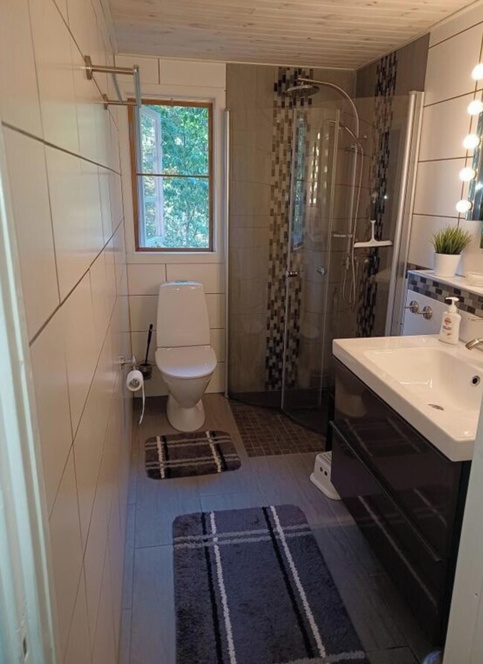 A bathroom with a toilet, shower, and sink.