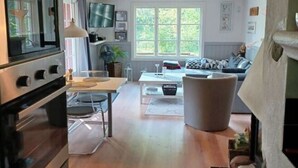 Uma cozinha moderna com forno embutido e uma área de refeições com mesa e cadeiras.