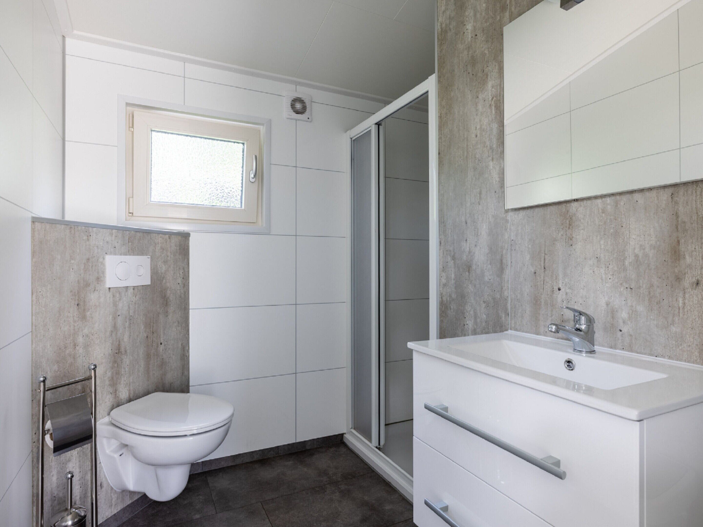 Une salle de bain moderne équipée de toilettes, d’une douche et d’un lavabo.