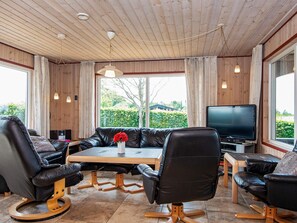 A modern living room with a sofa, chairs, a TV, and a wooden ceiling. - 4 Star Holiday Home in Glesborg (Glesborg)