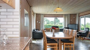 Uma sala de jantar ampla com mesa e cadeiras de madeira, um sofá e uma televisão.