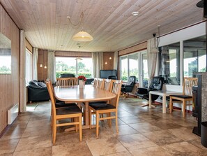 A spacious room with a wooden dining table surrounded by chairs, a sofa, and a television.