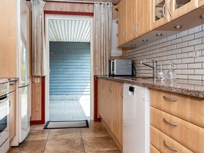 Une cuisine compacte avec des meubles en bois, un lave-vaisselle encastré et un four à micro-ondes.