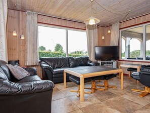Un salon moderne avec un canapé en cuir, une table basse en bois et un téléviseur à écran plat.