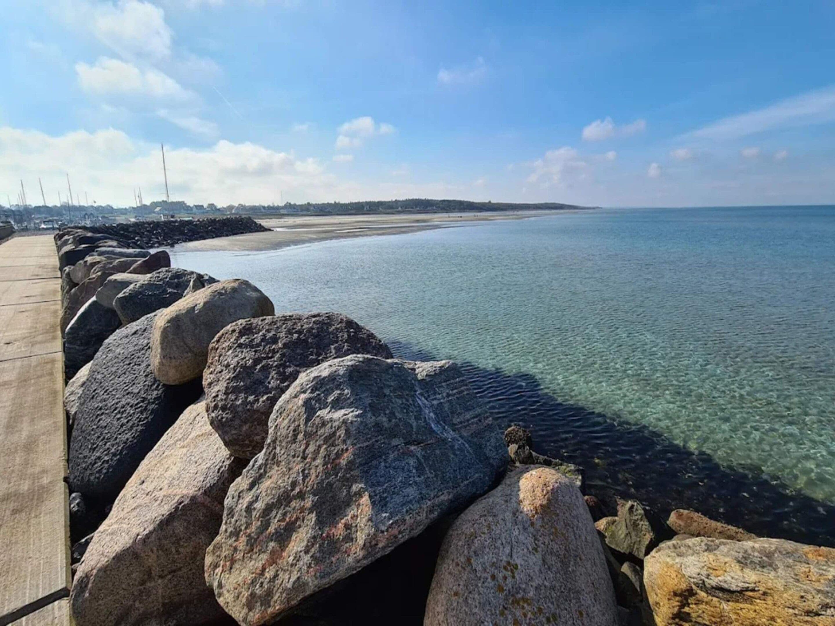 A coastal walkway with large rocks and a clear view of the sea.