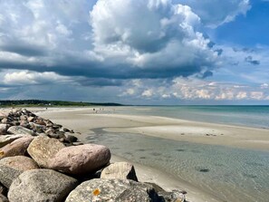 A beach with clear water, a rocky shoreline, and a cloudy sky. - 4 Star Holiday Home in Glesborg (Glesborg)