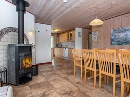 Ein gemütliches Zimmer mit Kaminofen, Holzstühlen und Fliesenboden.