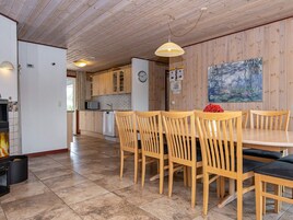 Un interior de madera con comedor, cocina y un cuadro en la pared.