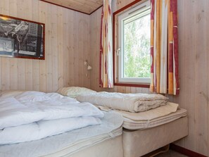 A bedroom with two beds, a window with curtains, a wall-mounted lamp, and a framed picture. - 4 Star Holiday Home in Glesborg (Glesborg)