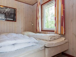 Un dormitorio con dos camas, una ventana con cortinas, una lámpara de pared e imagen enmarco.