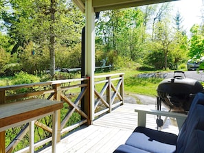 A wooden deck with a barbecue grill and seating area overlooking a forested area. - 4 Star Holiday Home in Norrtalje (Norrtälje)
