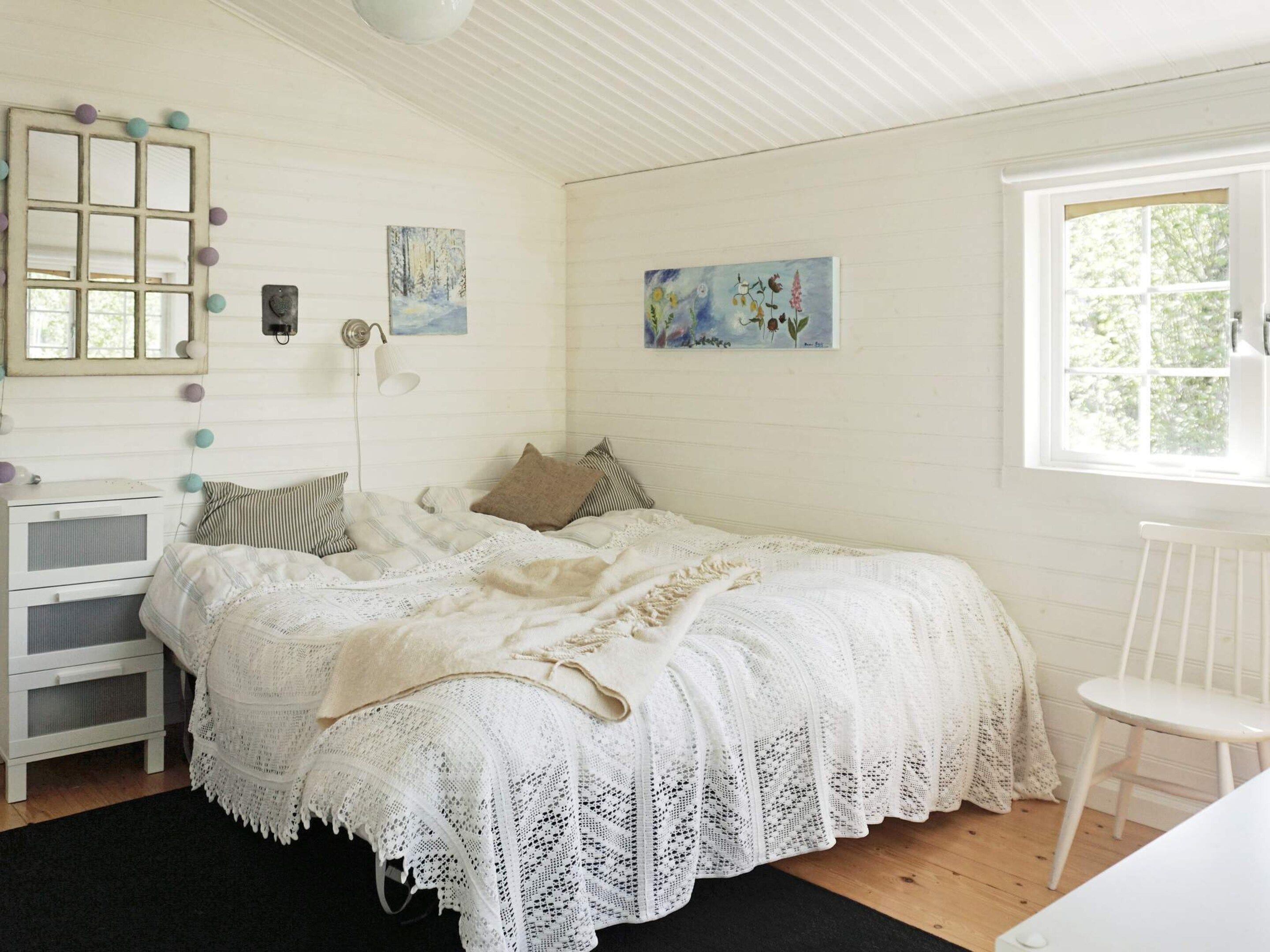 A bedroom with a bed, a nightstand, a dresser, and a window.