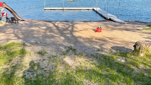 A lakeside beach with a wooden dock extending into the water, a red bucket, and a pair of chairs on the sand. - 4 Star Holiday Home in Norrtalje (Norrtälje)