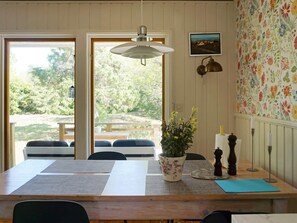 A dining area with a table, chairs, a hanging light fixture, a potted plant, and a wall with floral wallpaper. - 4 Star Holiday Home in Norrtalje (Norrtälje)