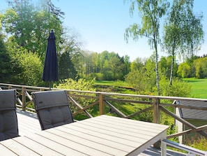 A wooden deck with a table and chairs, overlooking a green landscape with trees and a clear sky. - 4 Star Holiday Home in Norrtalje (Norrtälje)