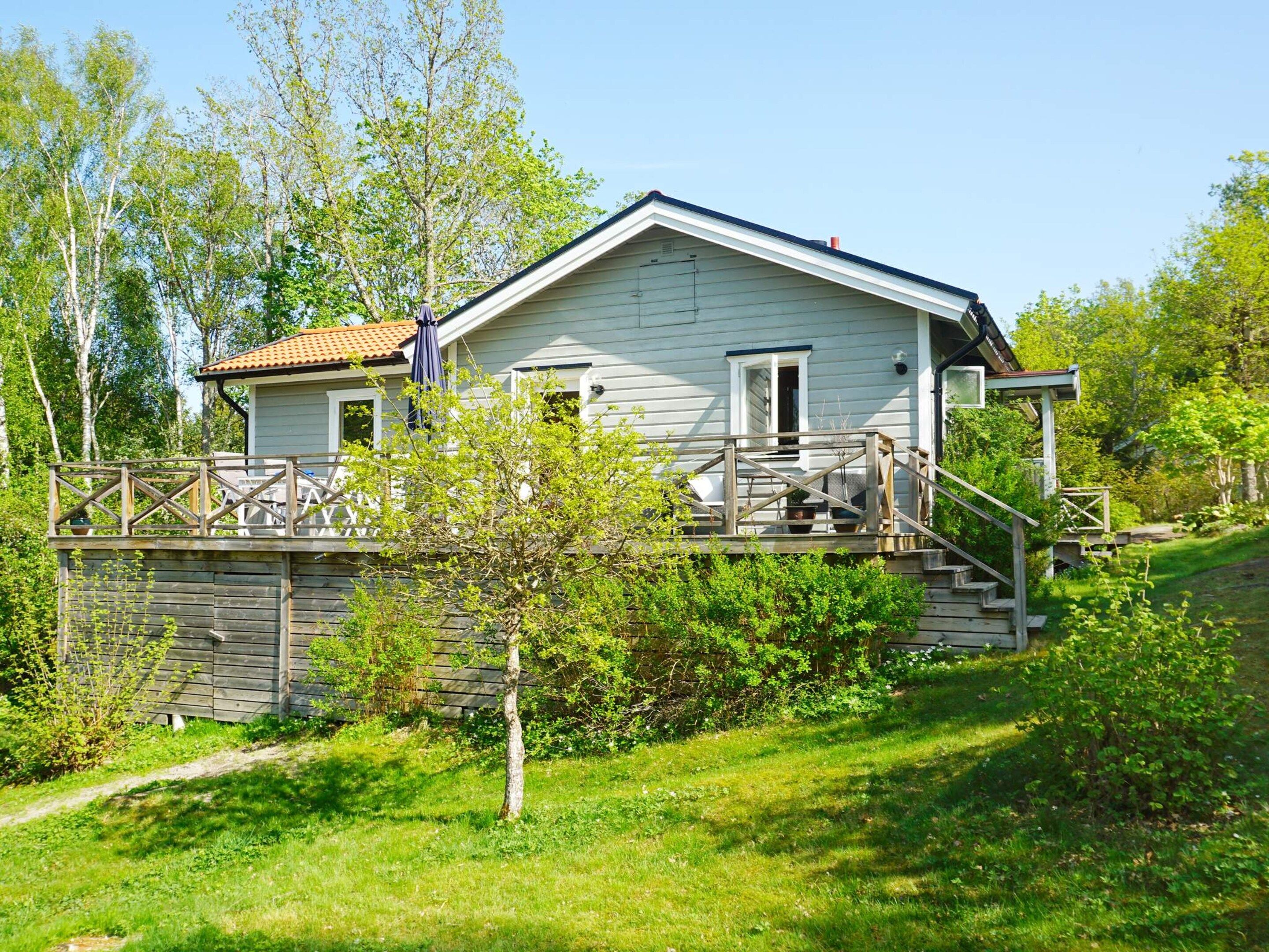 A two-story house with a wooden deck and a staircase leading to the entrance.