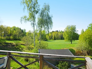 A wooden deck with a view of a green field and trees. - 4 Star Holiday Home in Norrtalje (Norrtälje)