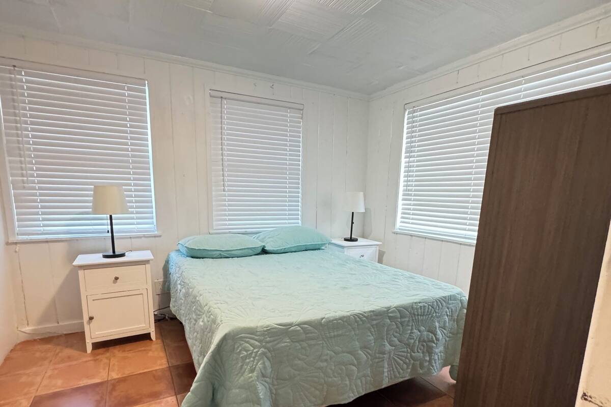 A bedroom with a bed, two bedside tables, a nightstand, and a wardrobe.