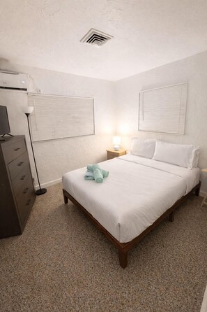 A bedroom with a bed, a dresser, a lamp, and a ceiling vent. - La Mare (Fort Lauderdale)